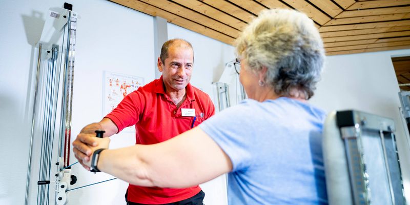 Sporttherapeut mit Patientin beim Gerätetraining