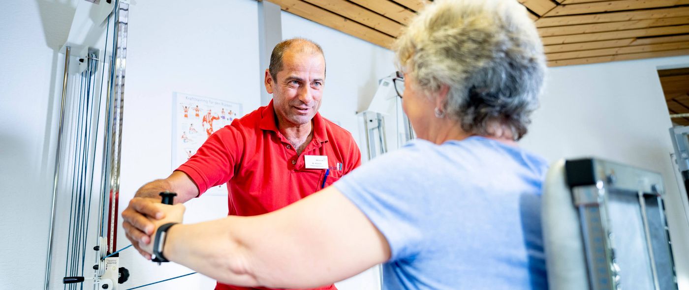 Sporttherapeut mit Patientin beim Gerätetraining