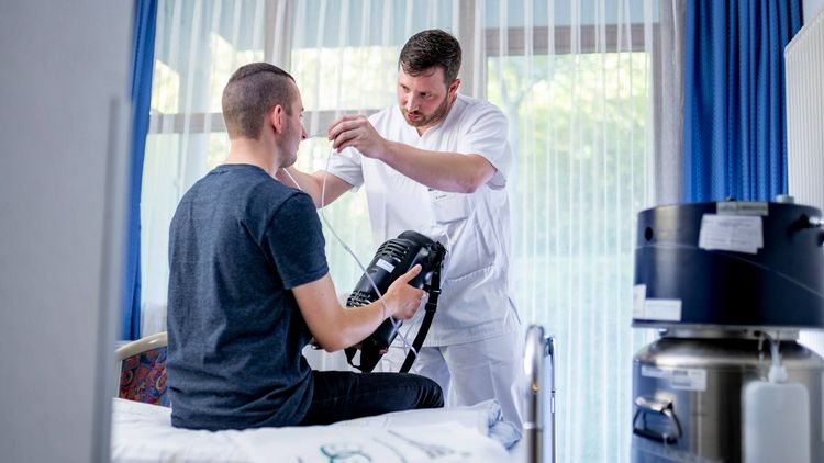 Patient mit Sauerstoffgerät am Bett
